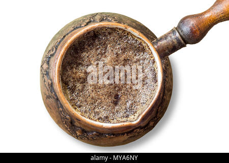 An old coffee maker made in the Middle East. Coffee foam on the surface. Turkish coffee . Isolated photo on a white background. Stock Photo
