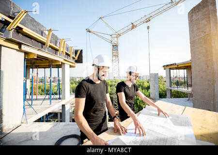 Workers with drawings at the construction site Stock Photo