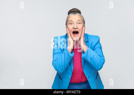 shocked aged woman. Emotion and feelings, Portrait of handsome expressive grandmother with light blue suit and pink shirt standing with collected gray Stock Photo