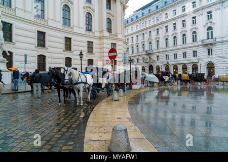 Vienna, Austria - October 22, 2017: Traditional carriages with horses waiting for tourists in the square in front of Hofburg Stock Photo