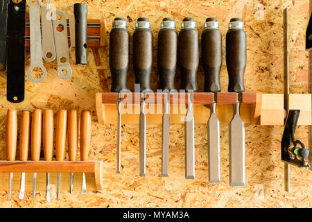 Carving tools hanging on the wall holder. The chisels aligned in the holder. View of the wall with tools. Stock Photo