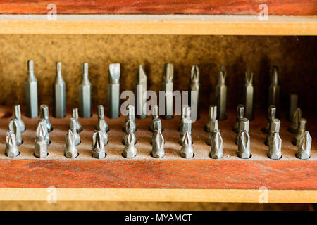 Set of dusty bits in a wooden holder in a workshop. Tools in a carving workshop. Stock Photo