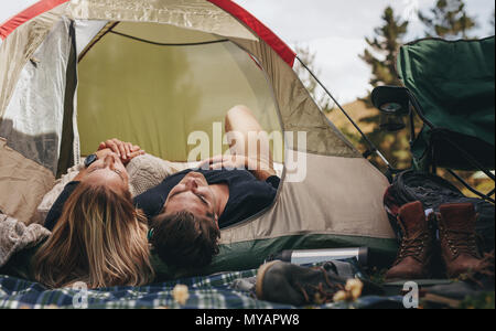 Man and woman lying together in tent. Couple sleeping in a tent on the campsite. Stock Photo