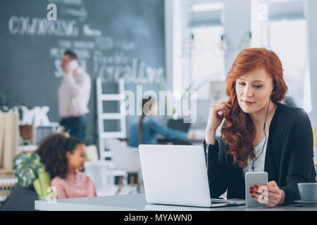 Relaxed, young worker of creative agency using laptop, listening music Stock Photo