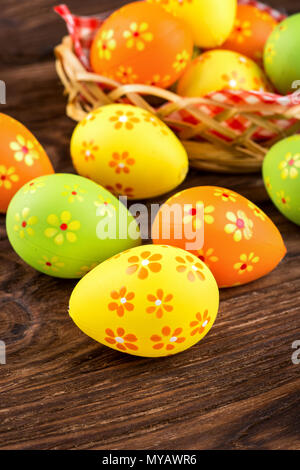 Scattered multi-colored Easter eggs with basket on the table Stock Photo