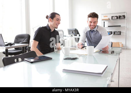 Two young businessmen working at a conference table in an office Stock Photo