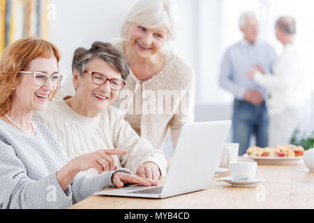 Three older women using laptop to watch photos Stock Photo