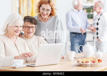 Senior woman teaching her friends how to use laptop Stock Photo