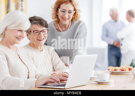 Three modern happy grandmothers using new technology laptop Stock Photo