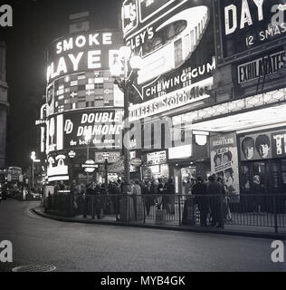 1964, historical picture, people outside the Pavilion Theatre at Piccadilly Circus, London, waiting to see 'A Hard Day's Night', the film starring the legendary British pop group, The Beatles, during the height of the craze of 'Beatlemania'. The band from Liverpool, England, transformed music in this era and the film was a major success. The road junction and public space was built in 1819 to join Piccadilly with Regent Street. In the city's West End some of the famous British brands of the day can be seen on the advertising billboards, including Players Cigarettes and Double Diamond beer. Stock Photo