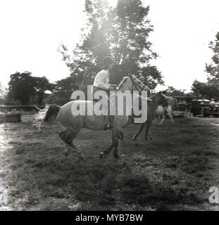 1964, historical, young female riding a horse in a field at an outdoor countryside equestrian event, Buckinghamshire, England, UK. Stock Photo