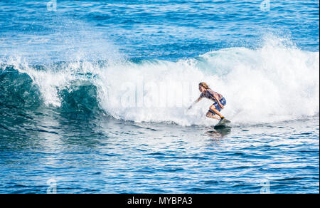 Young Caucasian man with long blonde hair surfing on wave in Pacific Ocean, Hanga Roa, Easter Island, Chile Stock Photo
