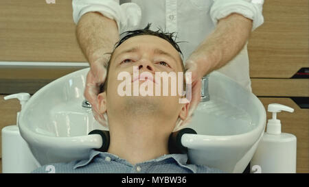 Professional hairdresser washing hair to her handsome client. Stock Photo