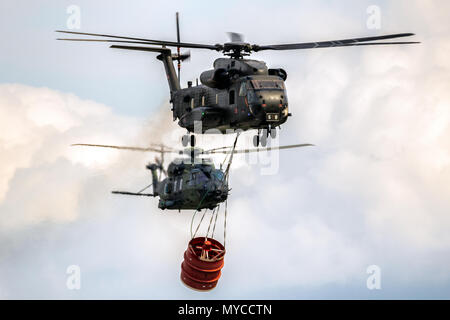 BERLIN - APR 27, 2018: German Air Force NH90 and CH-53 Stallion helicopter with a bambi-bucket during an aerial fire fighting demonstration at the Ber Stock Photo