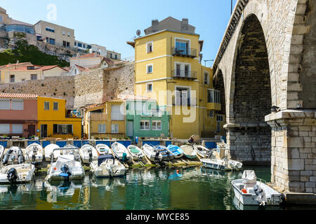 The small port of the Vallon des Auffes with boats moored in front of colorful houses right next to the road bridge of the Kennedy Corniche. Stock Photo