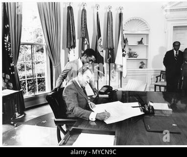 President Richard Nixon signing a paper while Sammy Davis, Jr Watches Stock Photo