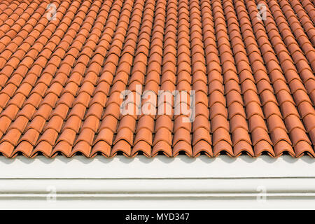 Red corrugated tile element of roof at house and white wall. Shingles roofing surface tiles overlay pattern and texture Stock Photo