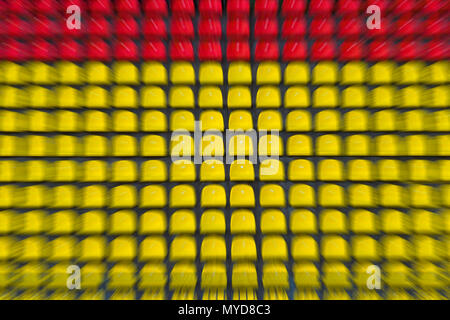 Empty red and yellow plastic chairs in a row at the football stadium. Zoom in effect. Stock Photo