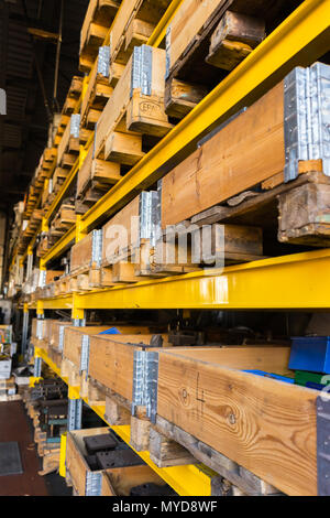 Warehouse storage shelf packed with wooden boxes and pallets containing heavy industrial metal utilities and parts. Shot from the side. Stock Photo