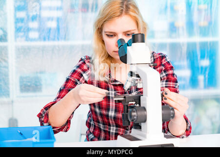 Biology lesson. Student using a light microscope. Stock Photo