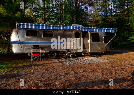 The iconic American made Airstream travel trailer sits in at a campsite at Driftwood Provincial Park in Ontario Canada. Stock Photo