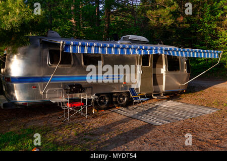 The iconic American made Airstream travel trailer sits in at a campsite at Driftwood Provincial Park in Ontario Canada. Stock Photo