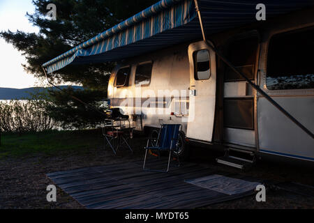 The iconic American made Airstream travel trailer sits in at a campsite at Driftwood Provincial Park in Ontario Canada. Stock Photo