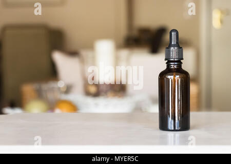 A brown glass medicine bottle with a dropper over a home indoor background. Stock Photo