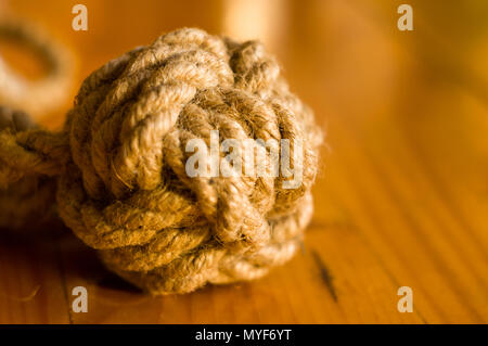 fender - marine knot of thick brown rope on a wooden background, closeup Stock Photo