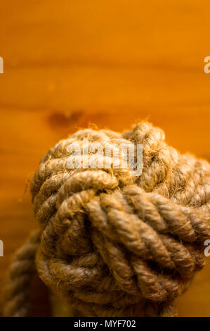 fender - marine knot of thick brown rope on a wooden background, closeup Stock Photo