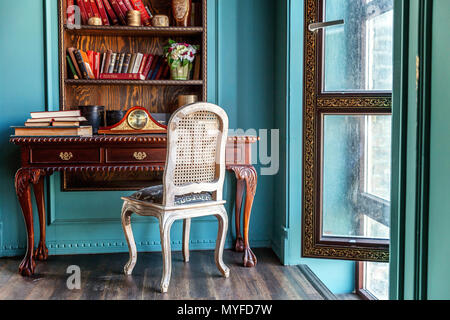 Luxury classic interior of home library. Sitting room with bookshelf, books, table and chair. Clean and modern decoration with elegant furniture. Educ Stock Photo
