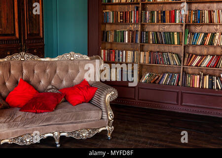 Luxury classic interior of home library. Sitting room with bookshelf, books, arm chair, sofa and fireplace. Clean and modern decoration with elegant f Stock Photo