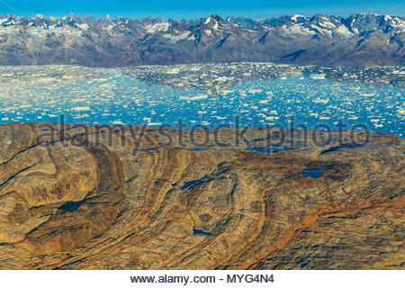 Aerial of folded metamorphic rocks and Icebergs in Sermilik Fjord. Stock Photo