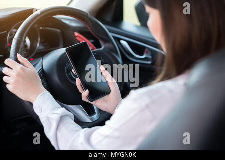 Young woman using smart phone while driving a car Stock Photo