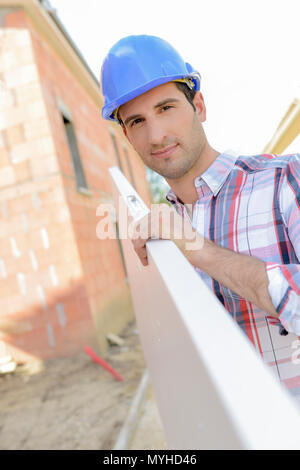 Builder carrying a large plank of wood Stock Photo