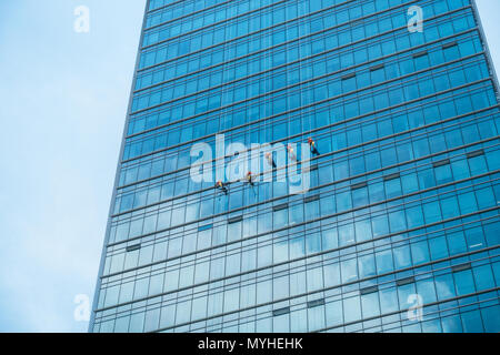 Window cleaners on face of glass office building in Shenzhen China Stock Photo