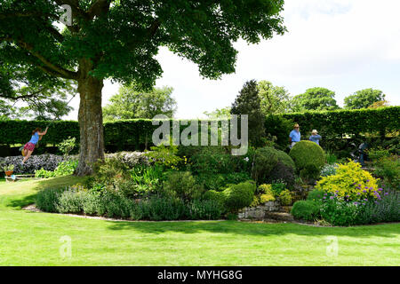 Visitors to the Open Gardens at Newton Valence perusing an English courtyard garden, Newton Valence, near Alton, Hampshire, UK. 20.05.2018. Stock Photo