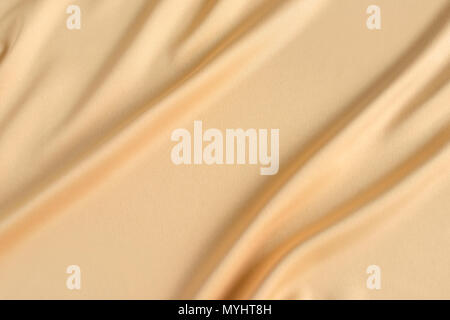 Close up of ripples in gold colored silk fabric. Satin textile background. Free copy space. Stock Photo