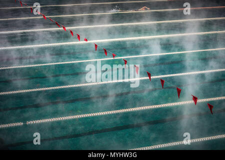 Corridor Lanes and flags in swimming pool with clean blue water. Fog over the water. Sport Competition. Stock Photo