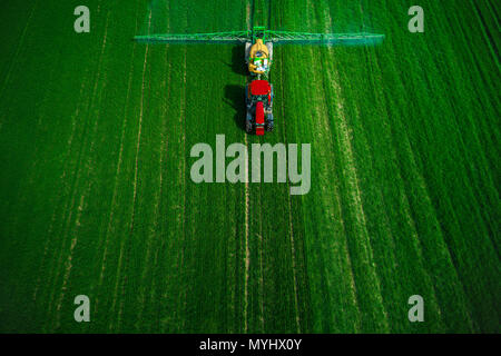 Aerial view of farming tractor plowing and spraying on field. Stock Photo