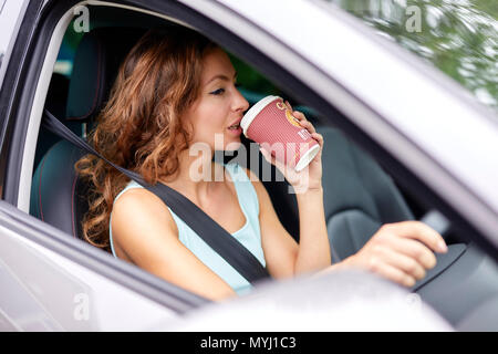 Woman drinking coffee whilst driving Stock Photo