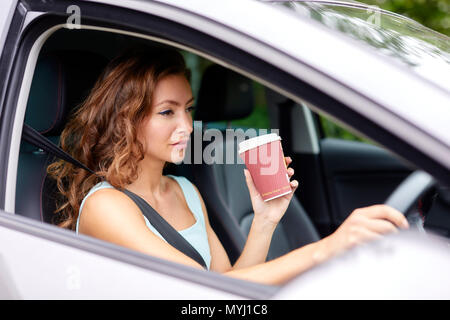 Woman drinking coffee whilst driving Stock Photo