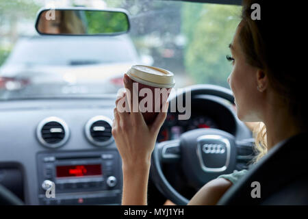 Woman drinking coffee whilst driving Stock Photo