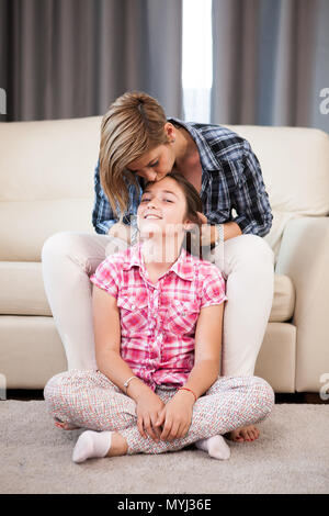 Beautiful mother kisses her daughter forehead Stock Photo