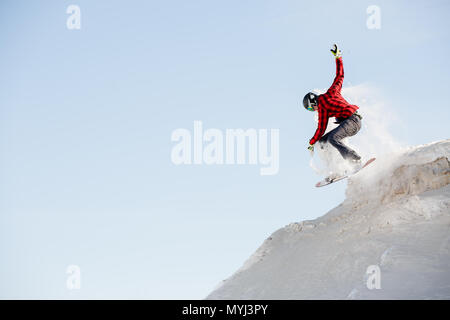 Photo of man in helmet with snowboard jumping from snowy mountain slope Stock Photo
