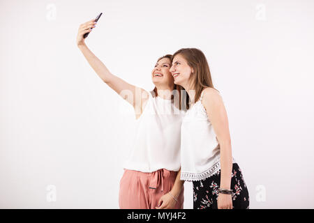 Two happy gorgeous young woman friends smiling and taking a selfie Stock Photo