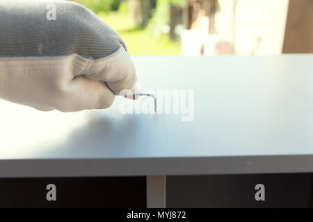 Man in protective gloves assembling furniture, kitchen cabinet. Domestic work. Craftsman. Carpenter. Stock Photo