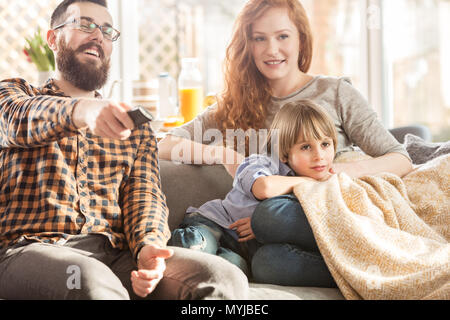 Happy family watching TV together on the sofa in the modern living room Stock Photo