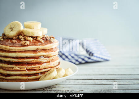 Pancakes with banana,walnut and muple syrup for a breakfast on wooden background closeup Stock Photo