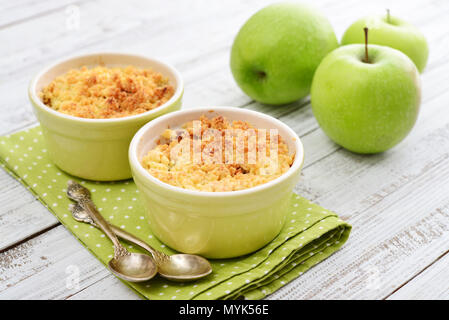 Apple crumble in small baking dish with fresh apples on wooden background Stock Photo